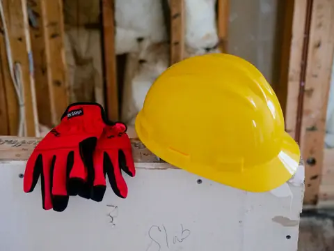 A yellow hard hat and red work gloves at a building site