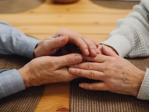 Two people holding hands across a kitchen table