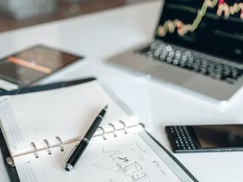 An open planner with notes beside a pen and a phone on a desk