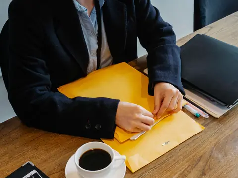 Hands opening a yellow folder beside a cup of coffee