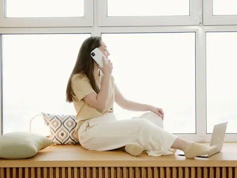 A person on a phone call by a sunny window