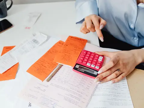 Receipts, forms and a calculator spread on a desk