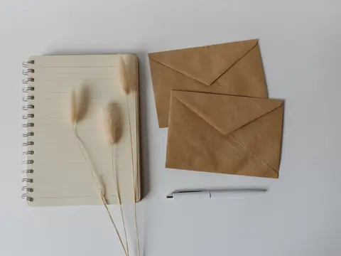 A notebook and two brown envelopes on a pale desk