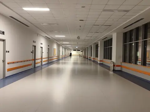 A long, bright hospital corridor with windows along one side