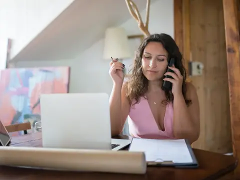 A person on a phone call making notes at a table