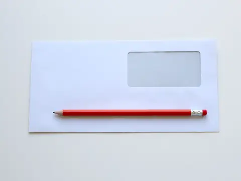 A white envelope and a red pencil on a desk
