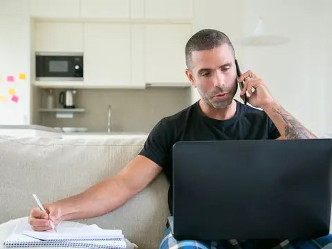 A person taking notes during a phone call at home