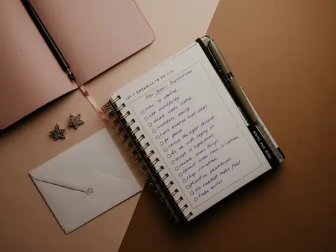 A notebook with a written list beside a pen and an envelope