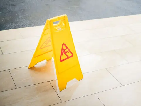 A yellow wet floor sign standing on a shiny tiled floor